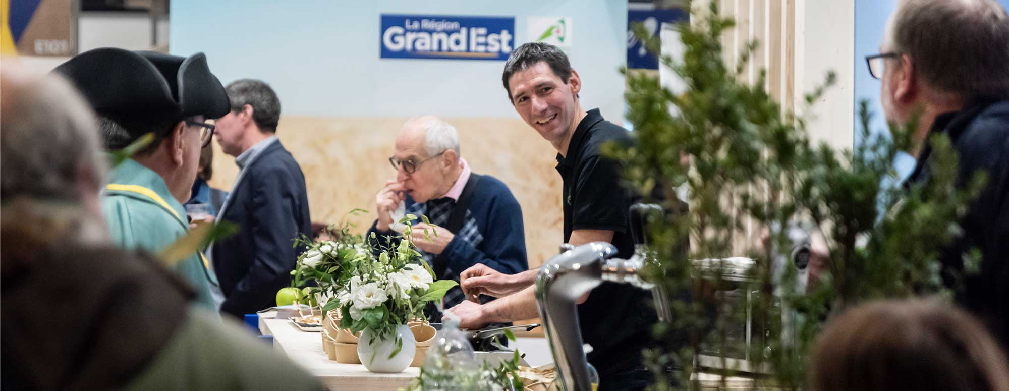 Exposant souriant derrière son stand de fleurs