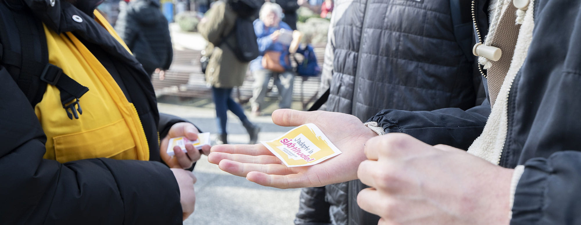 Visiteur tenant un tract SIA'TTITUDE dans les mains